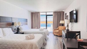 A hotel room with two beds, a desk, a chair, a TV, and a balcony with curtains. - LA74 Great studio right on the beach + pool (Myrtle Beach)