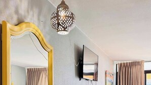 Zona pranzo con tavolo, sedie, uno specchio, una televisione e una lampada decorativa.