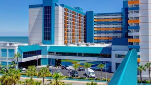 Un hotel moderno con un evidente cartello 'Landmark', diversi piani e un'area di parcheggio con auto e palme.