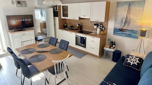Une cuisine moderne avec des armoires blanches, un four encastré et un coin repas comprenant une table et des chaises en bois.