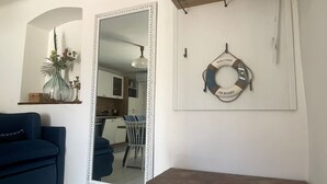 Une pièce avec un grand miroir, un banc en bois, une étagère fixée au mur et un panneau d’accueil.