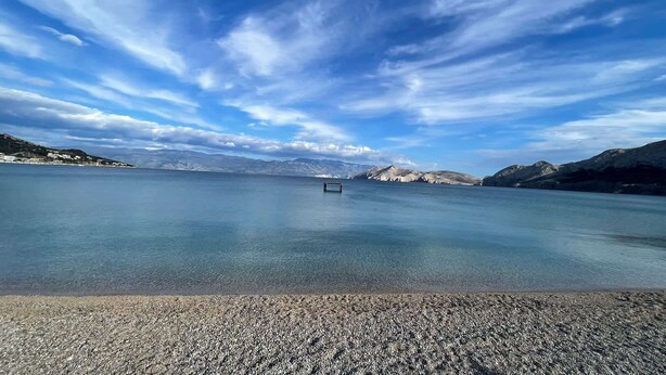 Un lac paisible, avec un ciel dégagé et des montagnes à l’horizon.