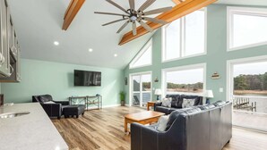 A spacious living area with a large sofa, a dining table, and a kitchen area. - Grays Inn Creek Waterfront Pvt Dock Kayaks & View (Rock Hall)