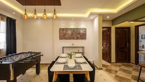A dining area with a foosball table, a painting on the wall, and a checkered floor. - Xuru Stays I Play Foosball & Do Yoga - 1 BR Apt. 5 Min To Airport (Cairo)