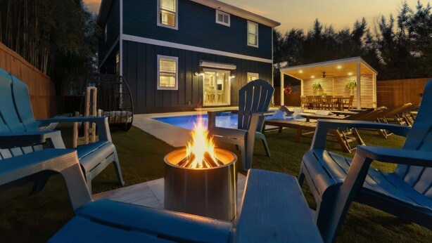 A modern house with a pool, outdoor seating, and a fire pit.