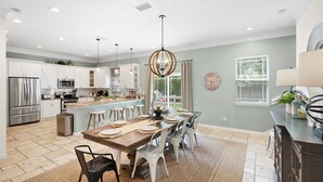 A modern kitchen with white cabinets, stainless steel appliances, and a central island with stools.