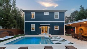 A two-story house with a swimming pool, outdoor seating, and a covered patio area.