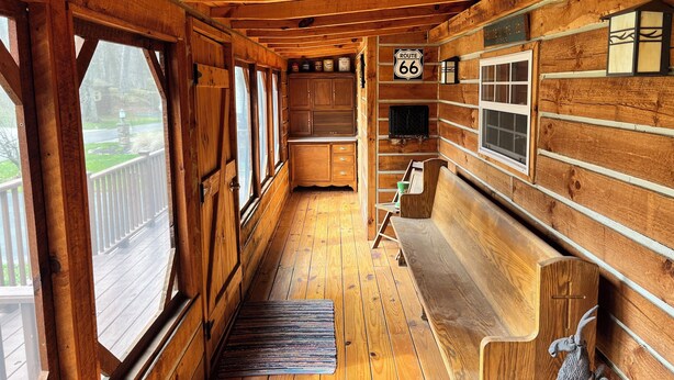 A wooden cabin interior with a kitchen area, wooden benches, and a sign indicating Route 66. - Cozy lake front cabin with WiFi, AC in awesome Angola (Angola)