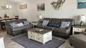 A living room with a brown leather sofa set, a white coffee table, and a blue rug.
