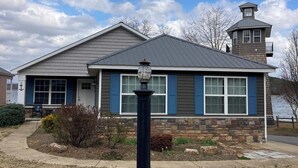 A house with a stone foundation, blue shutters, and a grey roof.