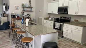 A modern kitchen with white cabinets, a granite countertop, and a central island with bar stools.