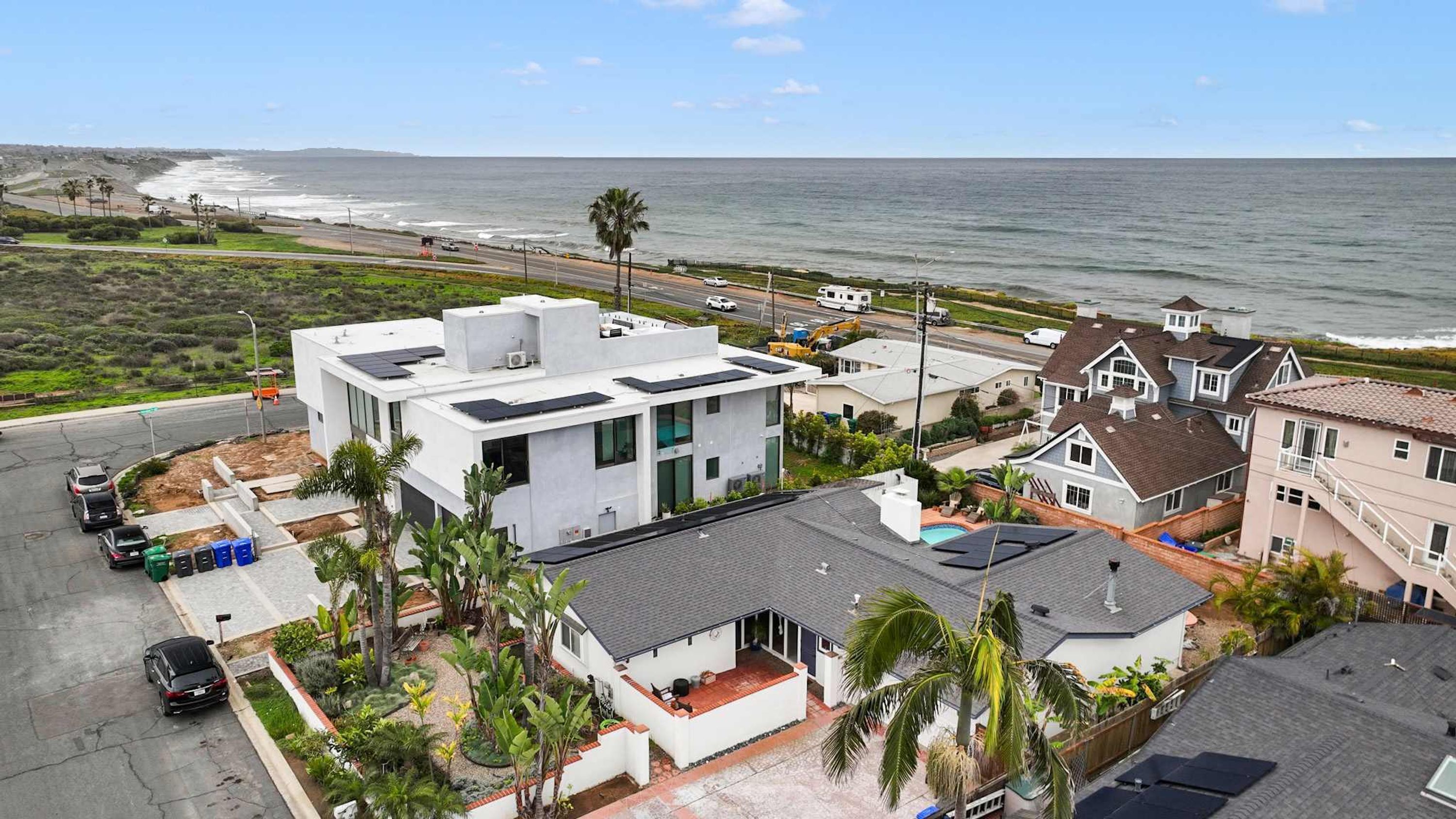 A modern house with a large patio, a swimming pool, and a view of the ocean.