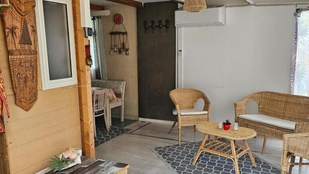 Ein gemütliches Zimmer mit einer hölzernen Bank, Korbsesseln und einem kleinen Tisch.