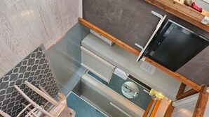 Ein hochwinkeliger Blick in eine moderne Küche mit Einbaukühlschrank, Holzschränken und einer Arbeitsplatte.
