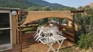 Ein Außenbereich mit Sitzgelegenheit, einer Holz-Pergola, weißen Kunststoffstühlen und einem Tisch.