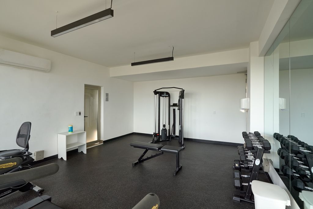 A gym with exercise equipment, a bench, and dumbbells.