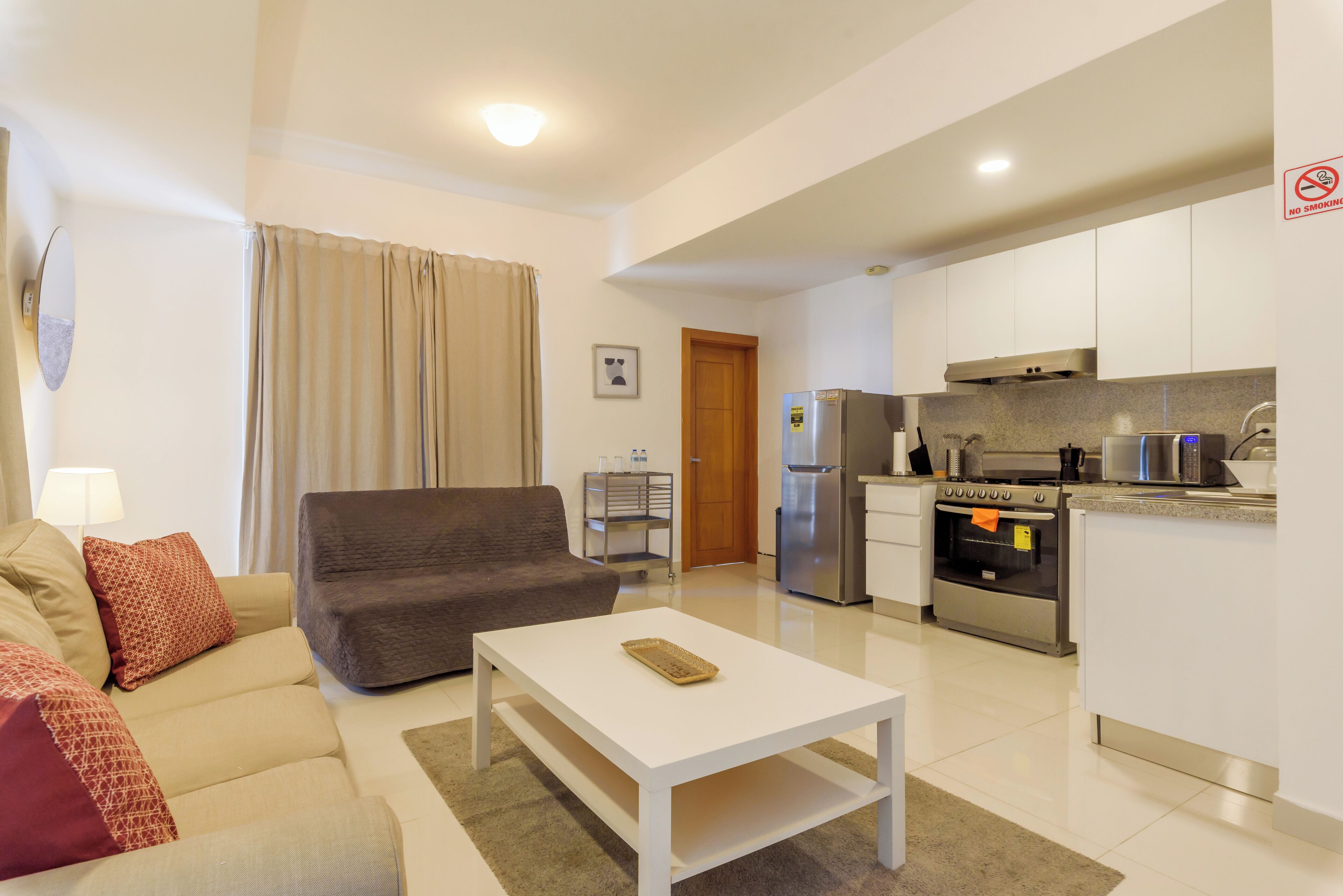 A modern living room with a sofa, a coffee table, and a kitchen area with appliances.