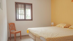 A bedroom with a bed, a chair, a window, and a wall lamp. - Come and explore the real Andalusia from our vacationhouses in the mountains (Guaro)