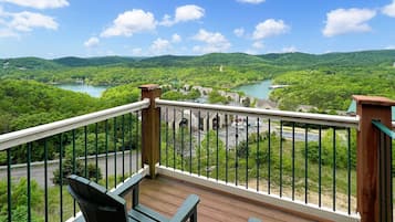 A balcony with a view of a river and green hills.