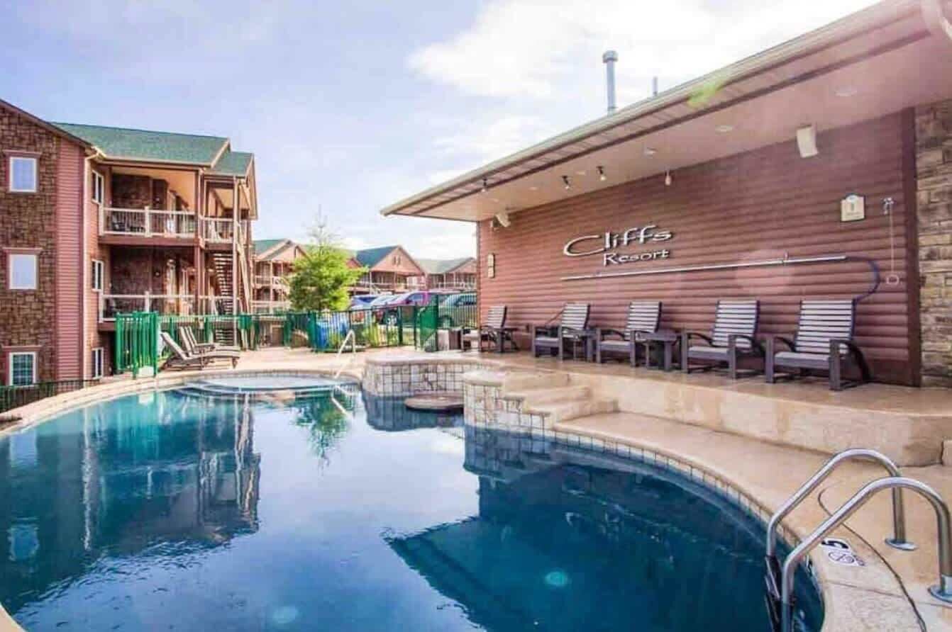 A hotel with a pool area, outdoor seating, and a building with a sign that reads "Cliffs Resort."