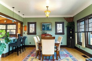 A dining area with a wooden table and chairs, a patterned rug, and a chandelier. - Historic Little Daisy Villa Sleeps 4 Sedona Views (Jerome)