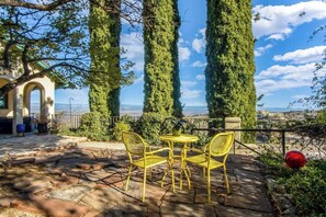 A patio with yellow chairs and a table, overlooking a scenic view with tall trees and a distant landscape. - Historic Little Daisy Villa Sleeps 4 Sedona Views (Jerome)