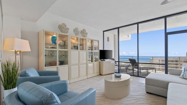 A modern living room with a large glass door leading to a balcony with a view of the ocean. - 2-Level Beachfront Resort Condo w/Views of Beach & Bay! (South Padre Island)