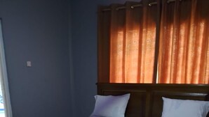 Une chambre à coucher avec un cadre de lit en bois, du linge de lit blanc et un tapis à motifs floraux.