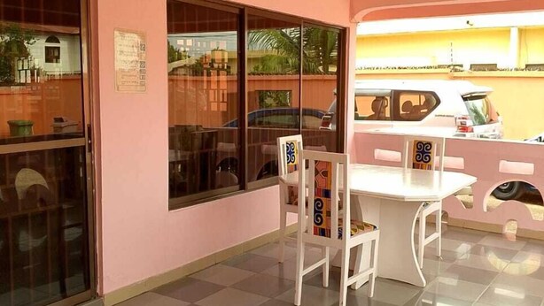 Une pièce avec un mur rose, une grande fenêtre, une table blanche et une chaise.