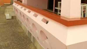 Un bâtiment rose avec un porche couvert, une petite fenêtre et une porte.