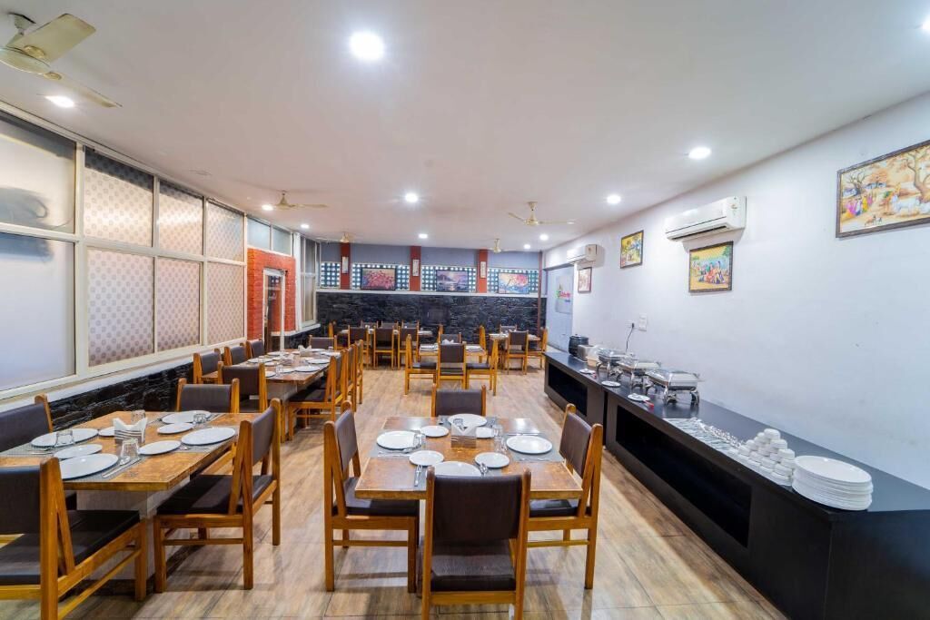 A spacious dining area with multiple tables and chairs, a kitchen counter with food items, and decorative wall art.