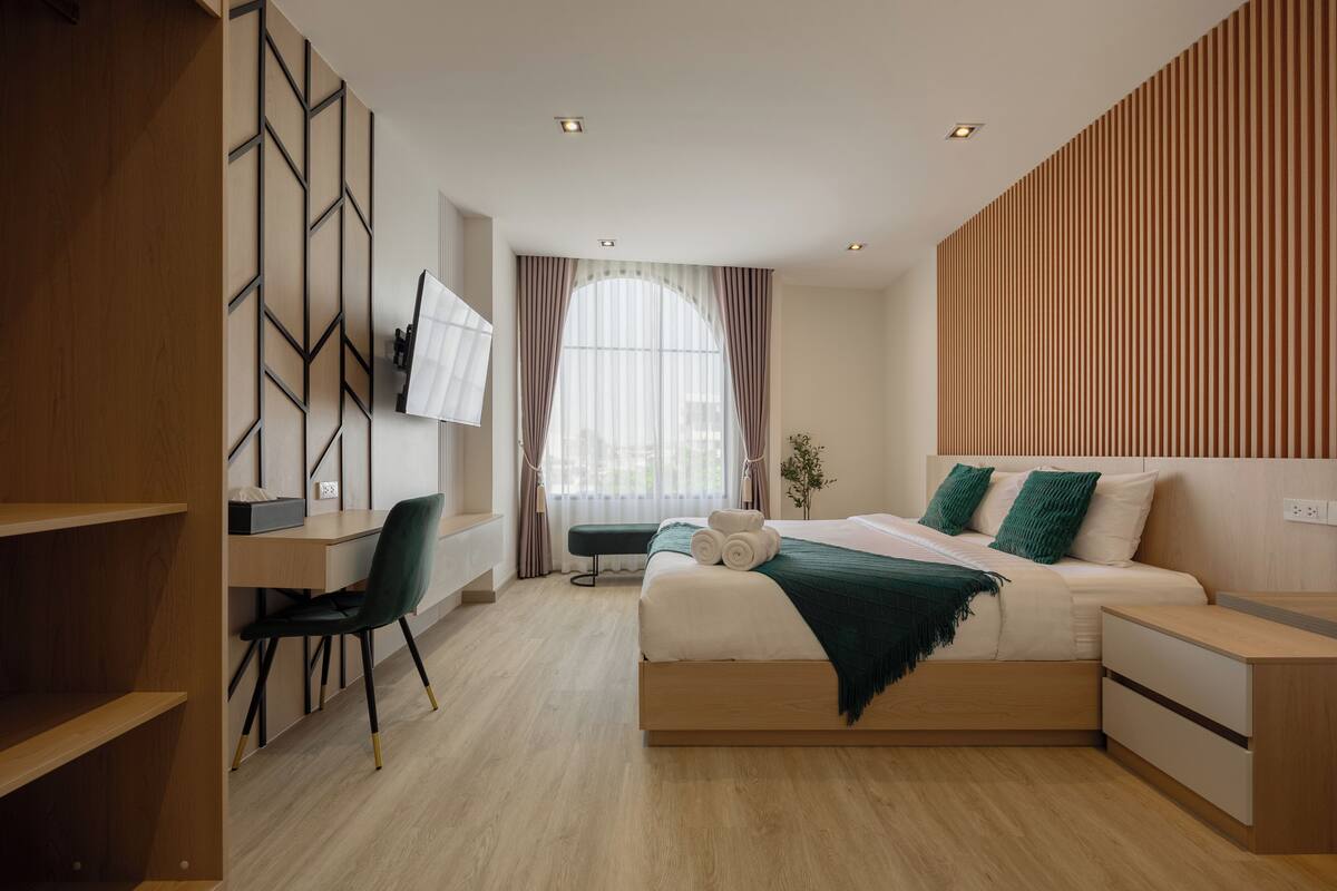 Quarto moderno com cama, mesas de cabeceira, escrivaninha e cadeira.