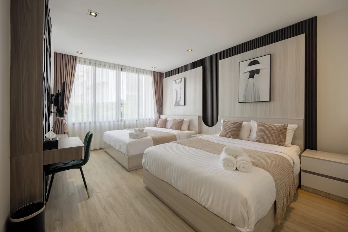 Quarto de hotel moderno com duas camas, uma escrivaninha e uma cadeira.