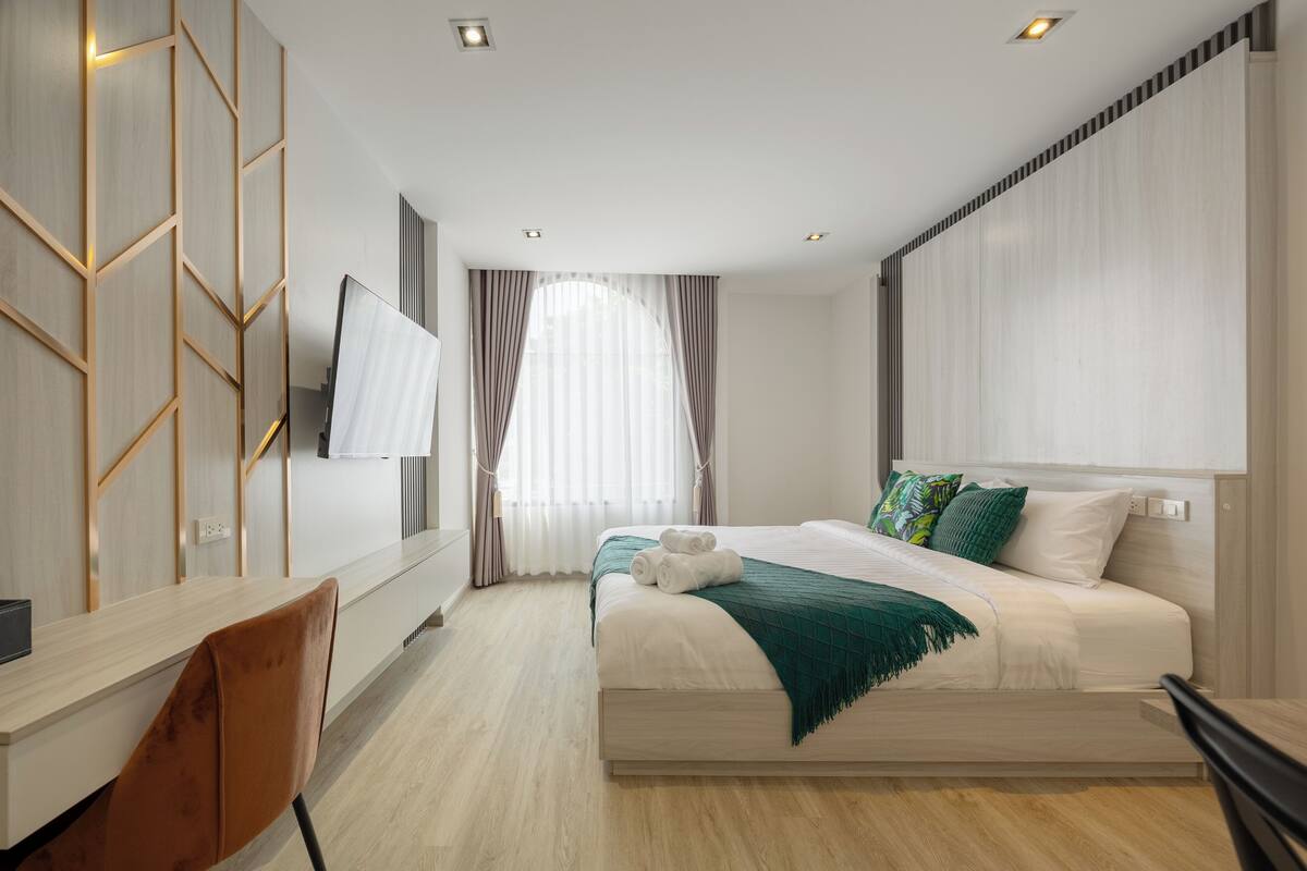 Quarto de hotel moderno com cama, escrivaninha e televisão.