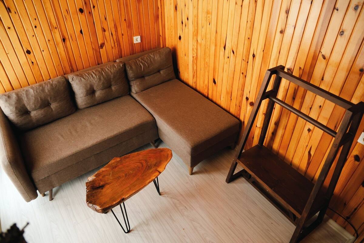 Una habitación con un sofá seccional marrón, una mesa de centro de madera y una silla de metal.
