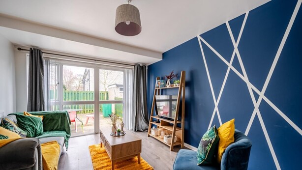 A modern living room with a blue accent wall, a wooden coffee table, a blue armchair, and a bookshelf. - Hillside Haven in Manchester (Manchester)