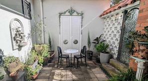 A small patio with a table and chairs, surrounded by potted plants and a decorative wall. - European Style Escape in Geelong (Geelong)