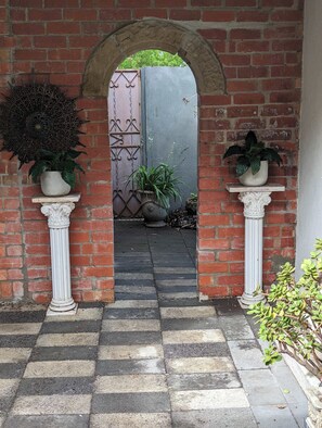 An arched brick entrance with a checkered pathway leading to a gate.