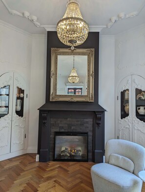 A room with a fireplace, a large ornate mirror, and a chandelier. - European Style Escape in Geelong (Geelong)