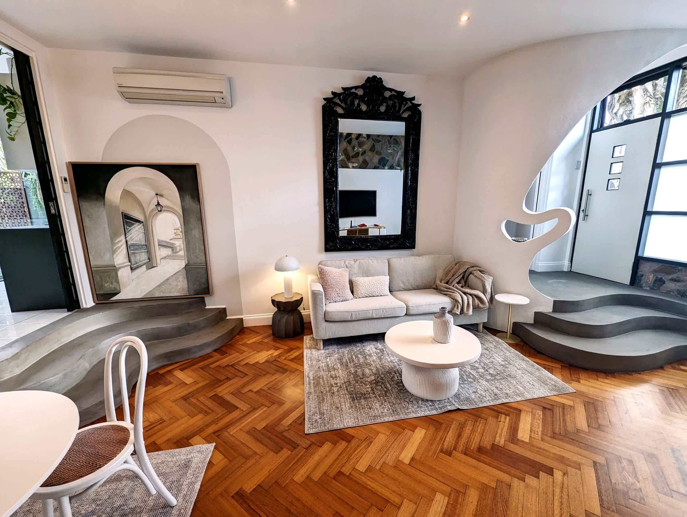 A modern living room with a sofa, coffee table, and a unique staircase.
