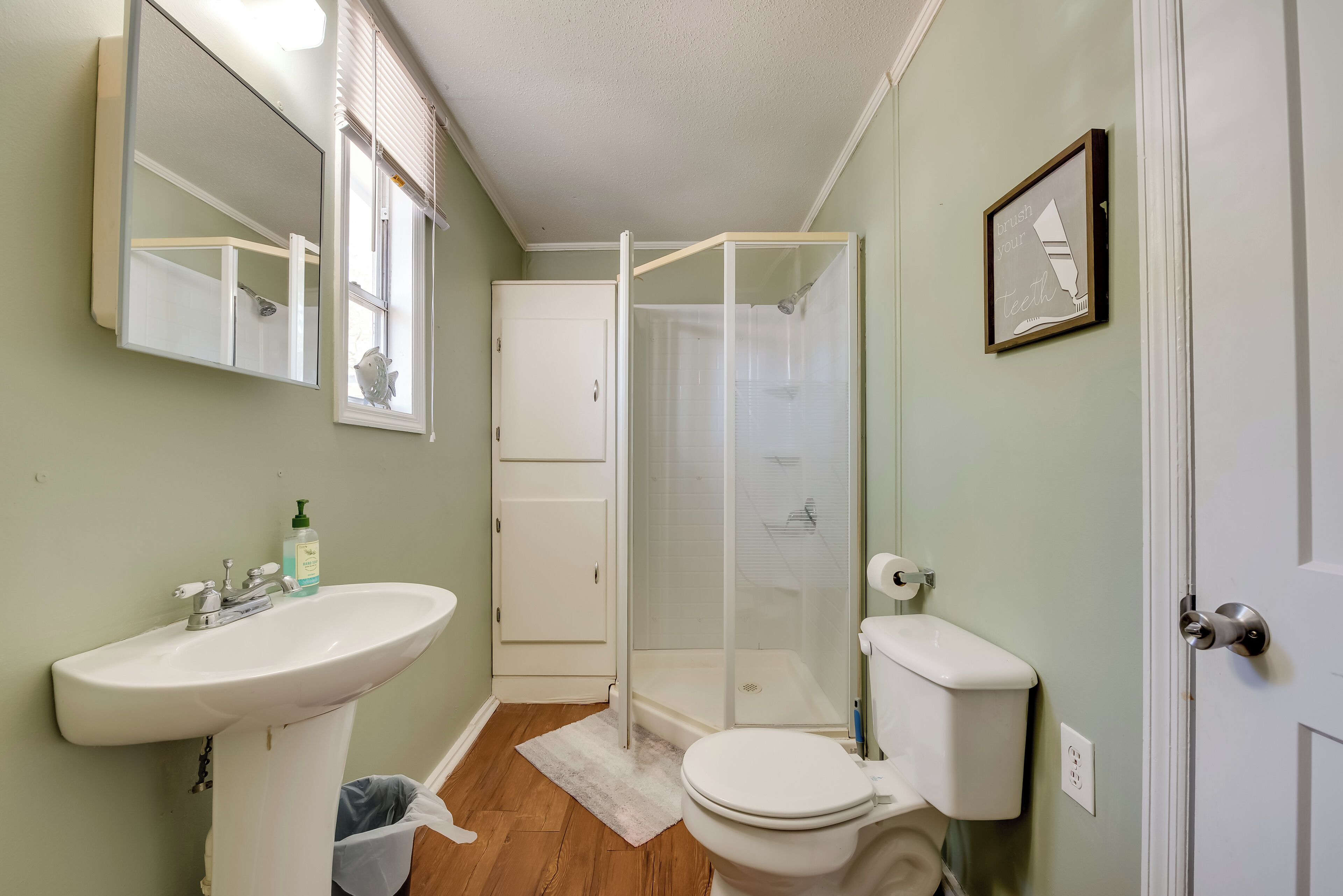 Un baño con lavamanos blanco, inodoro y cabina de ducha con paredes de vidrio.