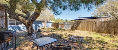 Un jardin avec un barbecue, une table et une chaise.
