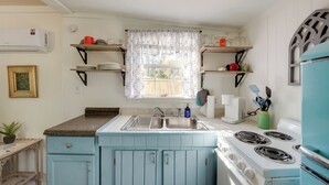 A kitchen with a blue stove, a sink, and a window with patterned curtains.