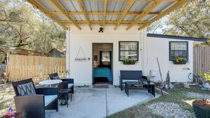 A covered patio area with outdoor furniture, a welcome sign, and a small building with a door.