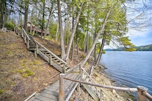 A wooden staircase leading to a cabin in a forested area by a lake.