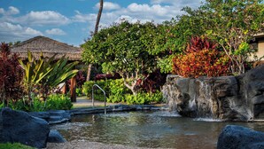 A tropical garden with a pond, rocks, and a thatched-roof structure. - Luxurious Kolea Kai Villa, Private Lanai w/ Ocean Views, Beach Club, Kona Coffee (Waikoloa Village)