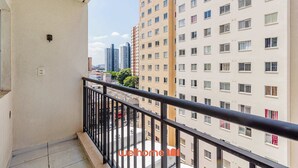 A balcony with a black railing overlooking a cityscape with high-rise buildings.