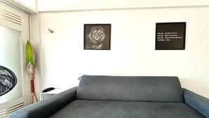 Una habitación con un sofá gris, un cuadro de un león enmarco y una frase motivacional en la pared.