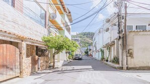 A narrow street lined with buildings, some with satellite dishes and power lines overhead. - Apartamento no Rio próximo à Lagoa da Tijuca (Rio de Janeiro)