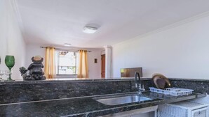 A modern kitchen with a granite countertop, a sink, and a dish drying rack. - Apartamento no Rio próximo à Lagoa da Tijuca (Rio de Janeiro)